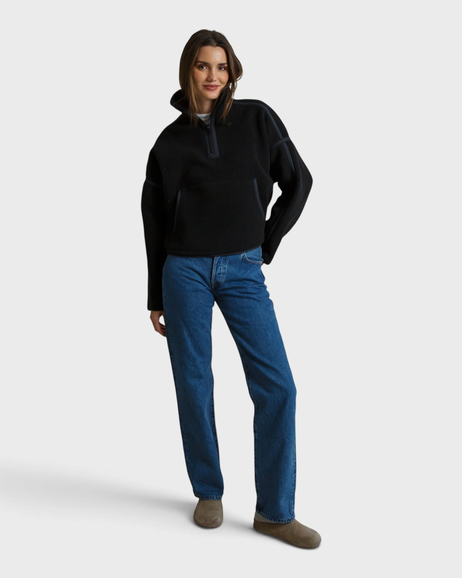 Model wearing a JONES + CO Tristan black sherpa half-zip pullover with blue jeans and neutral slip-on shoes.