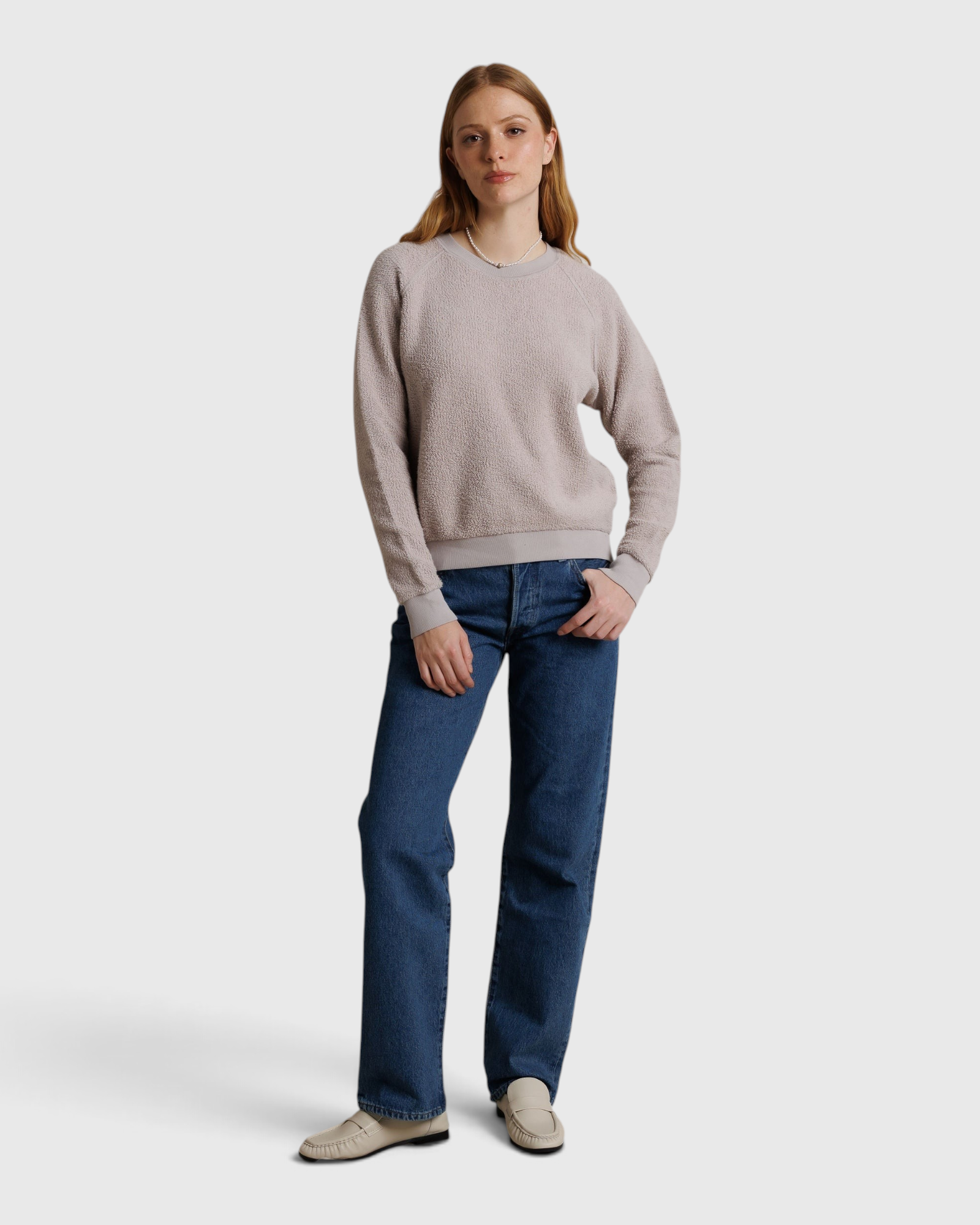 Model wearing a JONES + CO cloud gray textured crewneck sweatshirt with blue jeans and loafers
