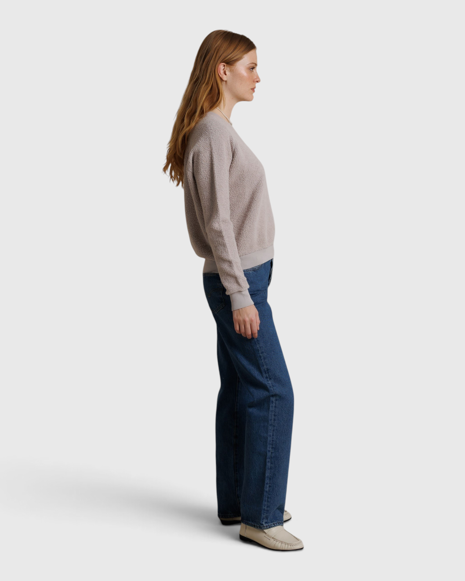 Model wearing a JONES + CO cloud gray textured Ziggy sweatshirt with blue jeans, side profile view.